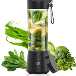 Black portable blender with green vegetables inside, surrounded by more vegetables on a white background